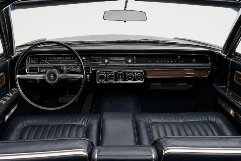 1964 Lincoln Continental interior showing the new single-sweep dashboard introduced for the 1964 model year replacing the twin-cowl design used from 1961 to 1963 running from one end of the instrument panel to the other without visual interruption with four HVAC outlets for more efficient cabin climate distribution and genuine leather seating throughout combined with the 24 hour road test quality standard applied to every Continental built at Lincoln's Wixom Michigan plant