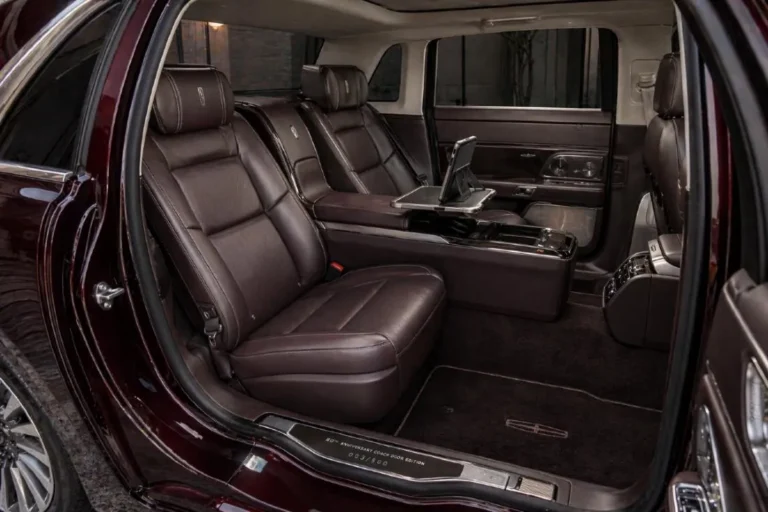 Rear passenger compartment of the 2019 Lincoln Continental 80th Anniversary Coach Door Edition showing the individual rear bucket seats with Bridge of Weir Scottish leather hand fitted by Cabot Coach Builders the pass through center console with stowable tray table and tablet holder with wireless charging pad the numbered interior door plaque showing the cars production number out of 80 and the extended legroom created by the 6 inch wheelbase stretch
