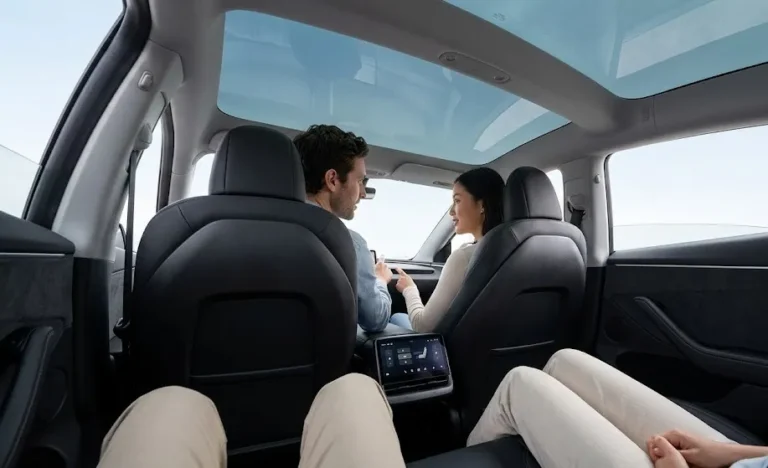2026 Tesla Model 3 Highland interior rear cabin showing the 8-inch rear touchscreen exclusive to the Highland refresh that allows rear passengers to independently control climate media and entertainment without requiring front-seat occupant interaction alongside rear seat legroom and the panoramic glass roof that provides the open cabin atmosphere standard across all three Model 3 variants with heated rear seats controlled independently through the rear screen