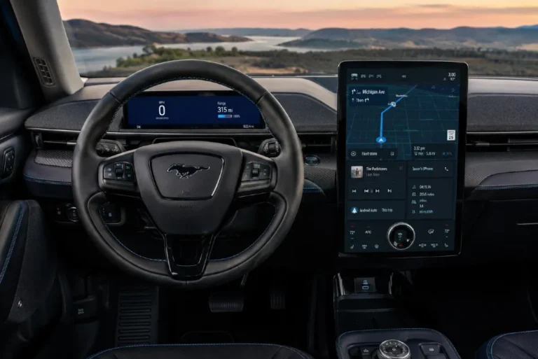 Ford Mustang Mach-E interior showing the 15.5-inch portrait-style center infotainment touchscreen and separate 10.2-inch digital driver instrument cluster with wireless Apple CarPlay and Android Auto standard across all trims alongside the Bang and Olufsen audio controls visible in the Premium and above trims and the overall cabin layout that places climate and audio controls within the touchscreen interface