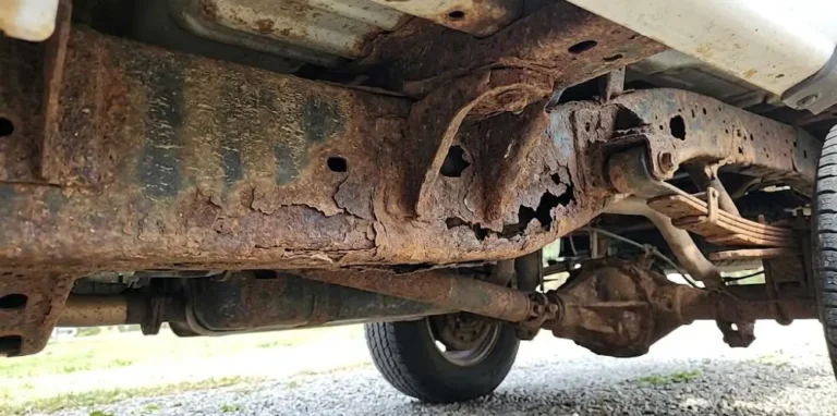 Significant frame rust on a pre-2019 generation GM truck frame showing structural corrosion in the lower frame rails and rear section areas most vulnerable to road salt exposure in northern states representing a well-documented reliability problem for 2007 through 2013 Chevrolet Silverado and GMC Sierra trucks in heavily salted winter road environments with prevention through annual professional undercoating regular undercarriage washing and inspection of hidden frame areas